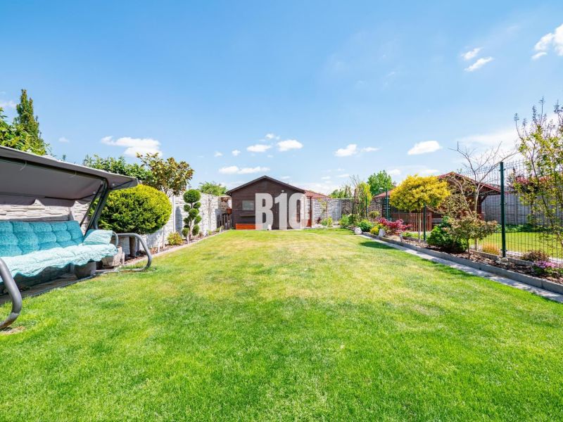 A garden of a family house in Nitra with a manicured lawn and a garden swing.
