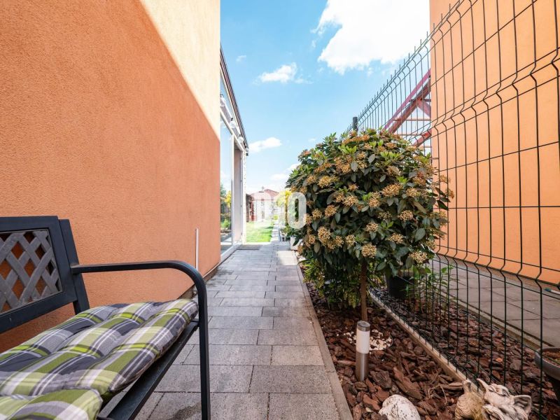 A family house in Nitra with a walkway, a bench, and a garden lined with greenery.