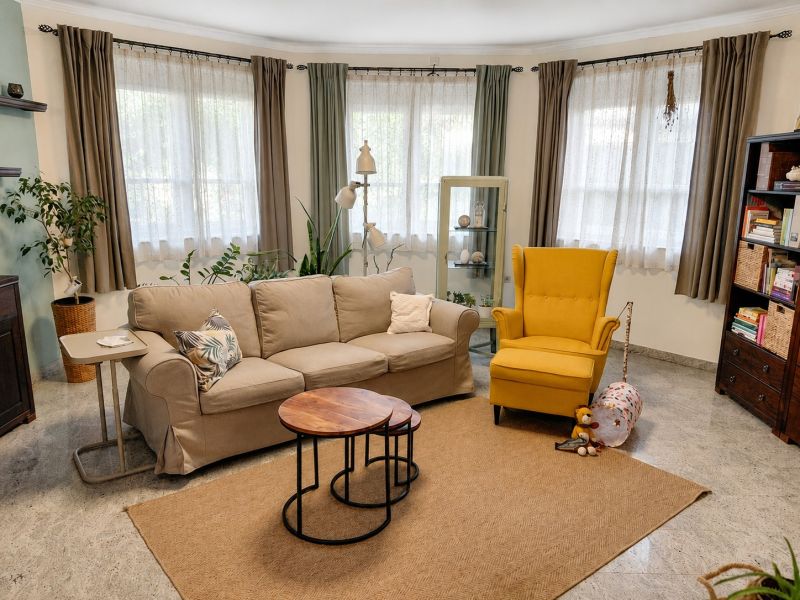 Living room in a family house with a sofa, a yellow armchair, and a bookshelf.