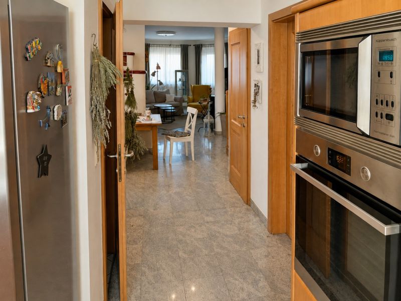 Modern kitchen with stainless steel appliances, open view into the living room in a family house.
