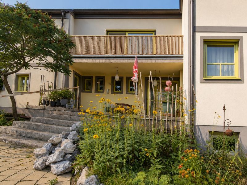 A family house in Podersdorf am See with stone stairs and a garden full of flowers.