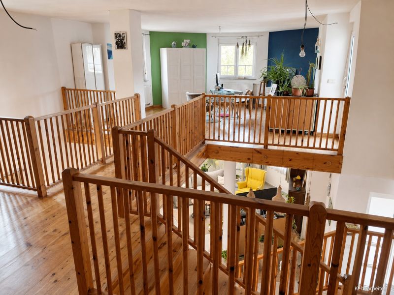 The interior of a family house with a wooden decor floor and wooden railing.
