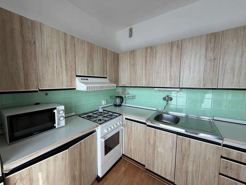 A kitchen in a 3-room apartment with a wooden decor floor and wooden cabinets.