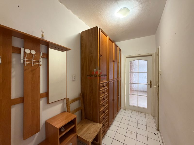 A hallway in a 3-room apartment with wooden decor and tiled flooring.