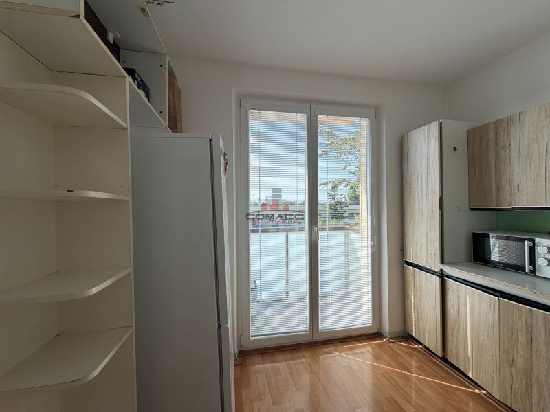 A kitchen in a 3-room apartment with a wooden decor floor and built-in cabinets.