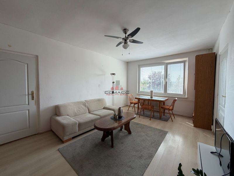 Living room in a three-room apartment with a wooden decor floor and a dining table.