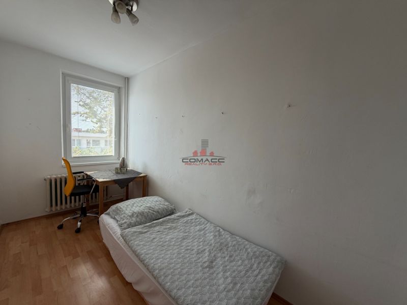 A room in a 3-room apartment with a bed, a table, and a floor with a wooden decor.