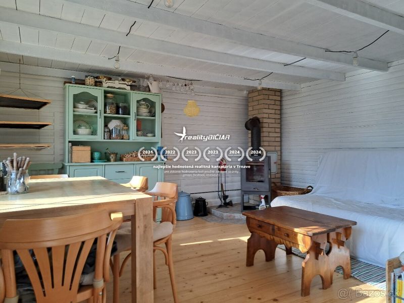 The interior of the cottage with a wood-patterned floor, wooden furniture, and a stove.