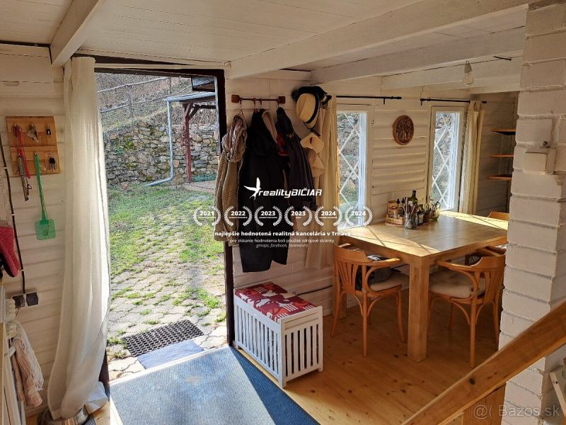 Wooden table and chairs in a cottage with a garden view.