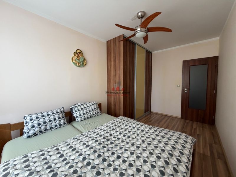 A bedroom in a 3-room apartment with a double bed, a built-in wardrobe, and a floor with a wooden decor.