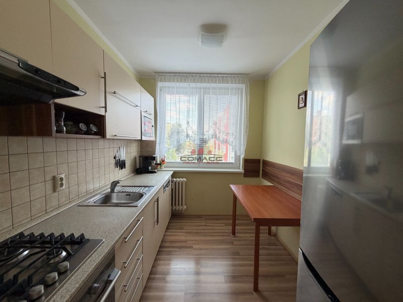 A kitchen in a 3-room apartment with a wooden decor floor and a kitchen unit.