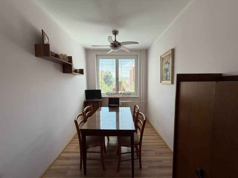 A dining room with a wooden table, chairs, and a floor with a wooden decor in a 3-room apartment.