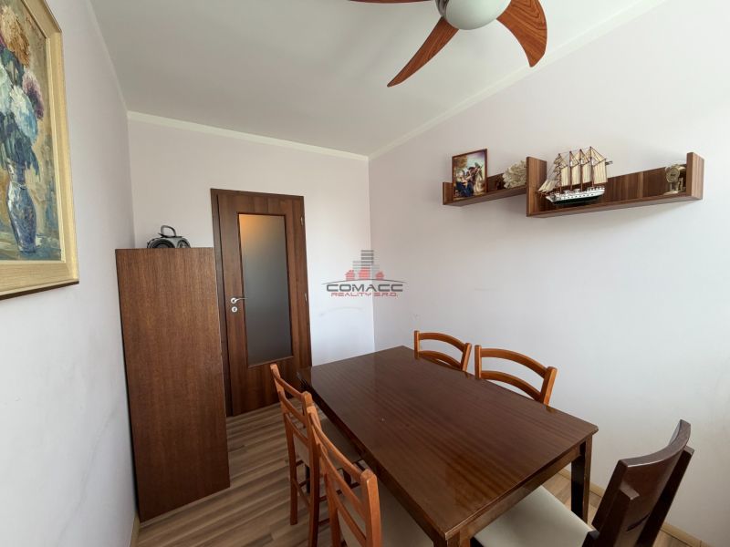 Dining room in a 3-room apartment with a wooden table and shelves.
