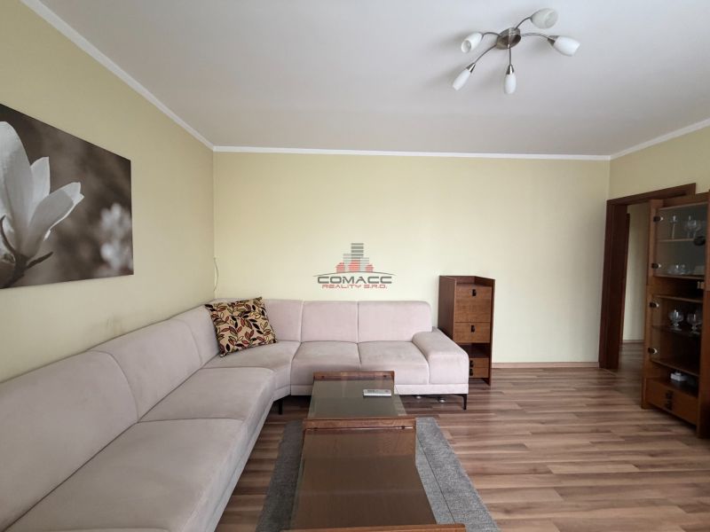 Living room in a 3-room apartment with a corner sofa and a floor with a wooden decor.