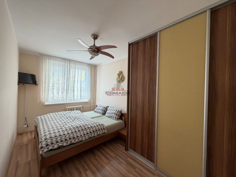 Bedroom in a 3-room apartment with a bed, wardrobe, and floor with wooden decor.