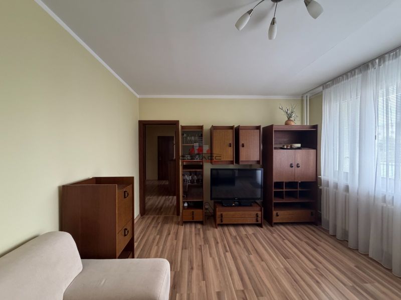 Living room in a three-room apartment with furniture and flooring featuring a wooden decor.