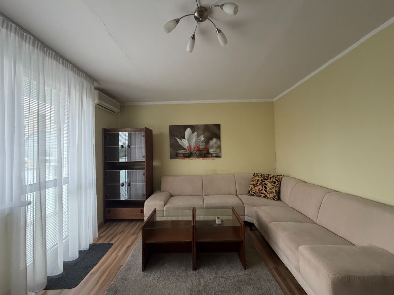 Living room in a 3-room apartment with a sofa, wood-patterned flooring, and a wardrobe.
