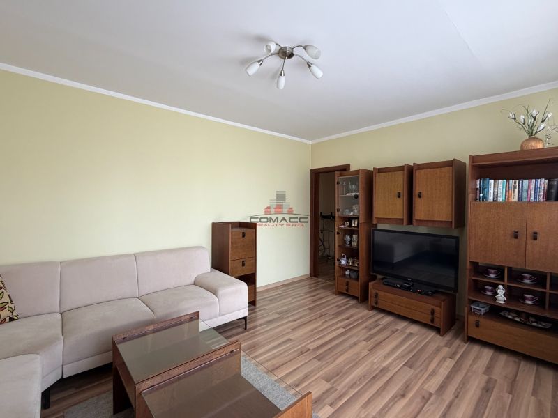 A living room in a three-room apartment with a wooden decor floor and furniture.