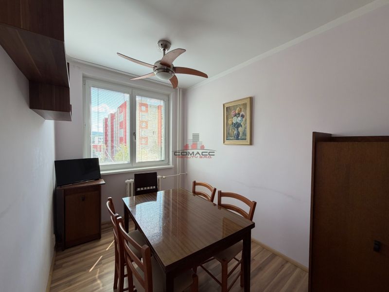 Dining area in a 3-room apartment with a wooden table and floor with a wooden decor.