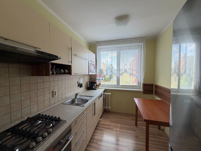 A kitchen in a 3-room apartment with a wood-patterned floor and a dining table.