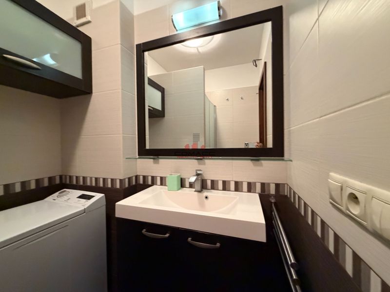 Bathroom in a 3-room apartment with a sink, washing machine, and a mirror on the wall.