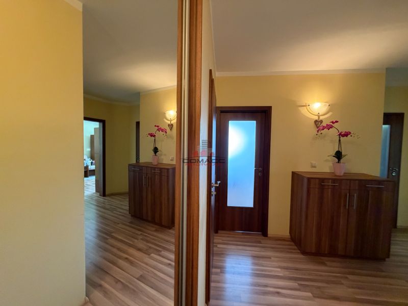 A hallway in a 3-room apartment with a wood-patterned floor and built-in cabinets.