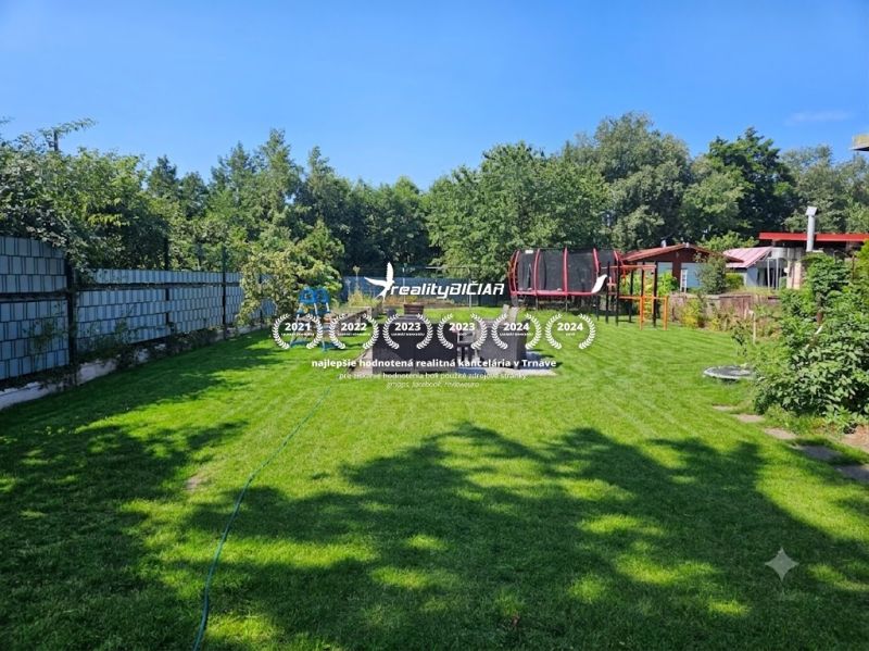 Mowed lawn in the gardens at Kamenný mlyn in Trnava, surrounded by trees.