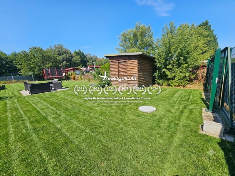 Grassy gardens in Kamenný mlyn in Trnava with a wooden shelter and a trampoline.