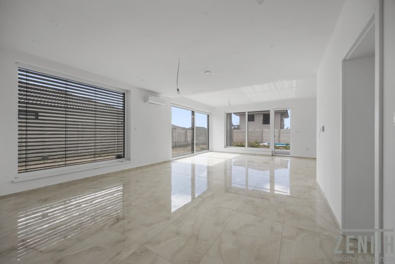 Spacious living area in a family house with large windows and glossy tiles.