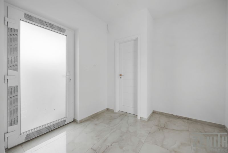 White entrance room in a family house with tiles and doors.