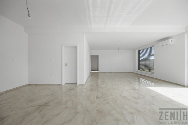 A spacious room with a large window and a wooden decor floor in a family house.