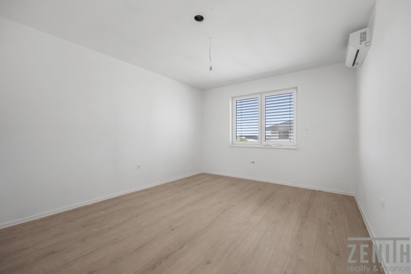 An empty room with white walls, a wooden decor floor, and air conditioning in a family house.