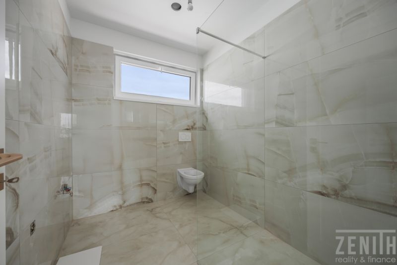 Bathroom of a family house with walls and floor in tiles of light shades.