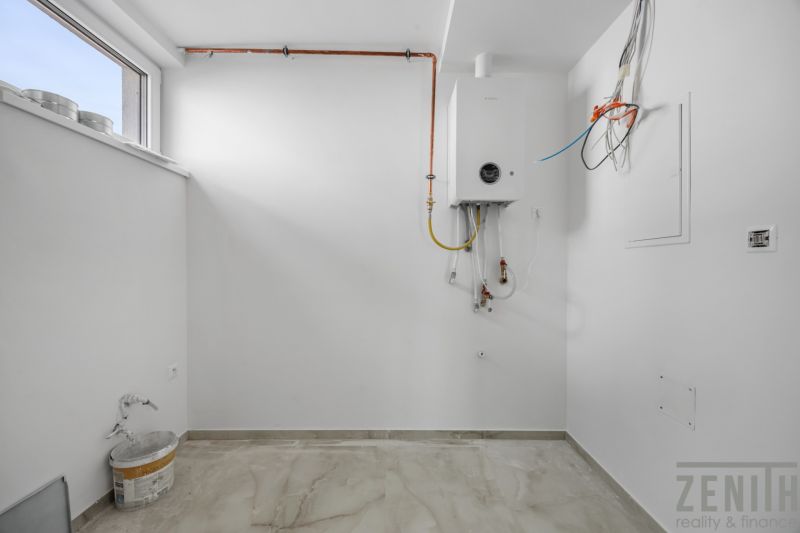 A white room with a boiler and a wooden-patterned floor in a family house.