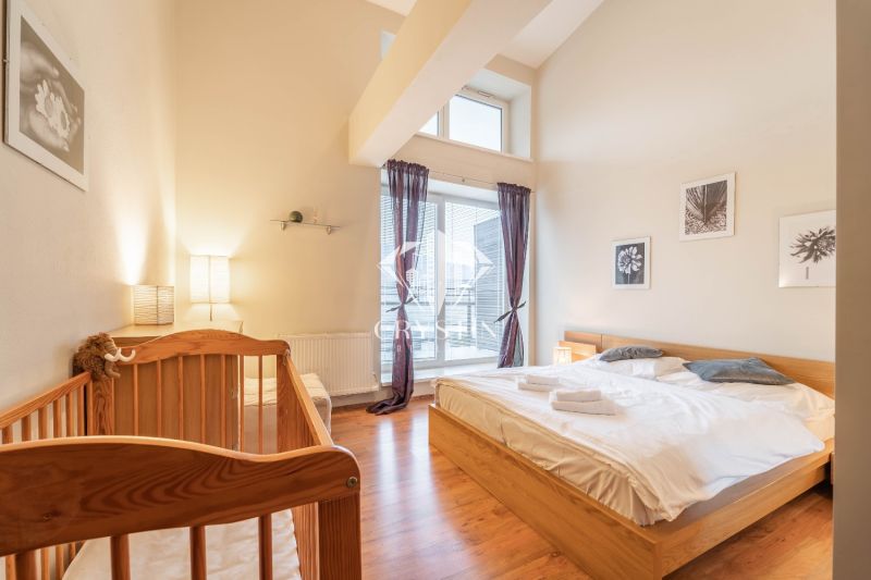 Bright bedroom in a holiday apartment with a crib and wood-patterned flooring.