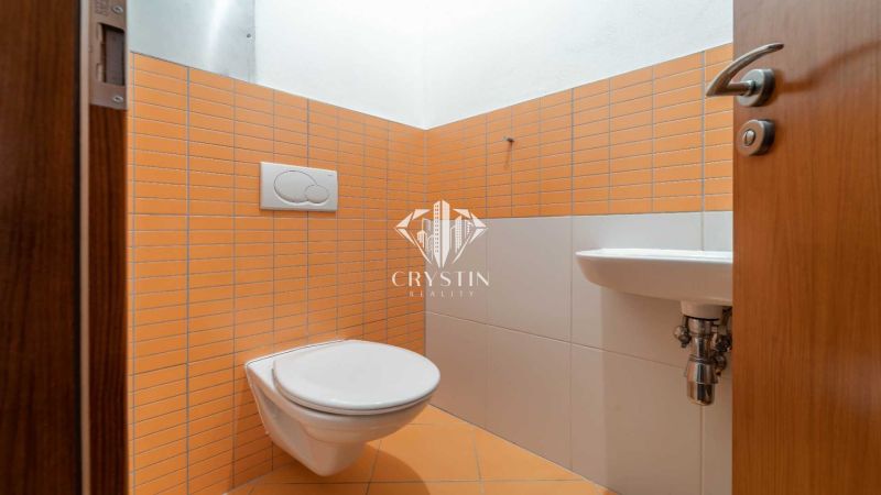 Bathroom in a holiday apartment with orange tiles and a wall-mounted toilet.