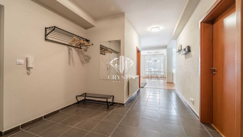 Hallway of a recreational apartment with tiles, a mirror, and a coat rack.