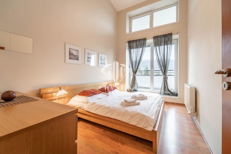 A bright bedroom with a double bed and a wooden decor floor in a holiday apartment.