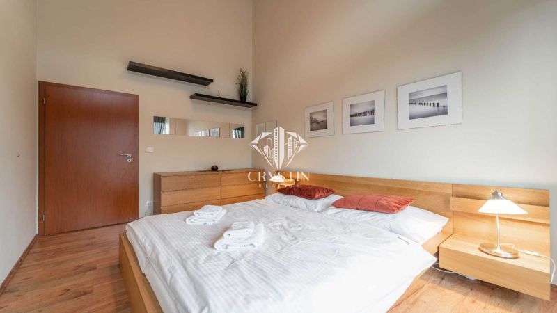 Bright bedroom in a holiday apartment with wood-patterned flooring and simple furnishings.