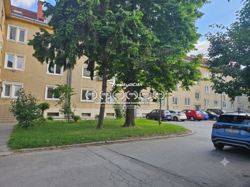 Parking lot near 3-room apartments on Študentská Street in Trnava, surrounded by greenery and trees.