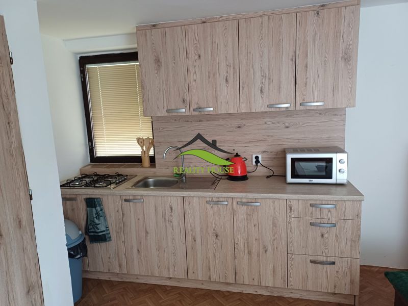 A kitchen with a wooden decor floor, cabinets with wooden decor, and appliances.