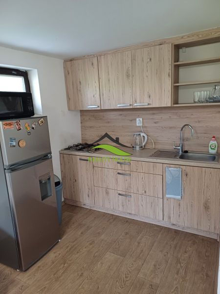 A kitchen unit with a wooden decor floor and appliances in a cottage.