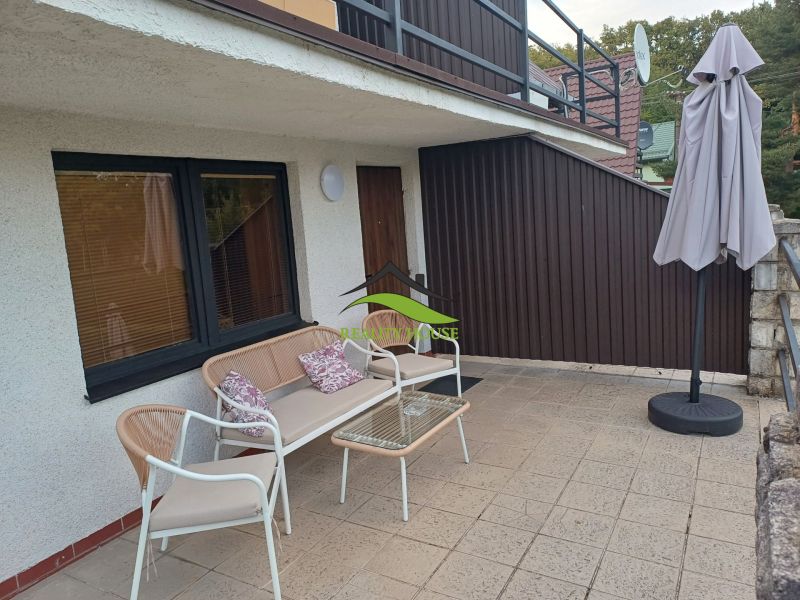 Terrace of the Cottage in Kaluža with seating and a sunshade.
