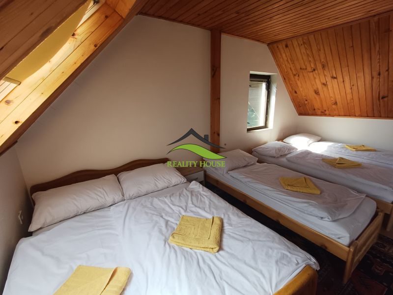 Attic room in the cottage with five beds and a wooden ceiling.