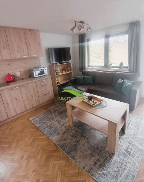 Living room in a cottage with wood-patterned flooring, a sofa set, and a coffee table.