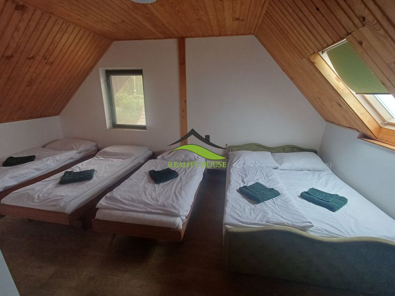 A bedroom in a cottage with three beds and a wooden decor floor.