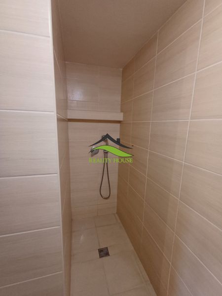 Bathroom with a barrier-free shower and light ceramic tiles in the cottage.