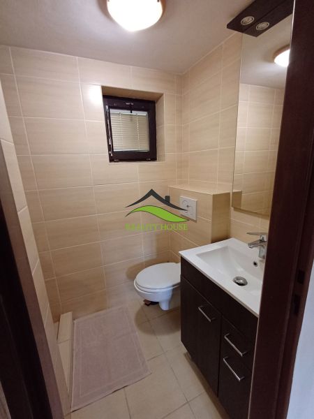A bathroom with light tiles, a sink, and a toilet in a cabin.