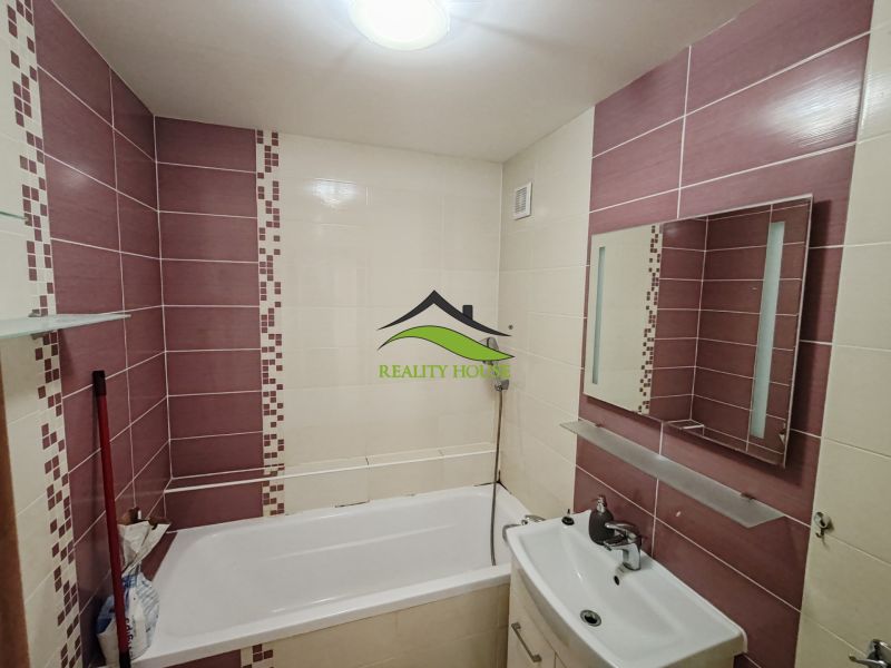 A bathroom in a 3-room apartment with a bathtub, a sink, and purple tiles.