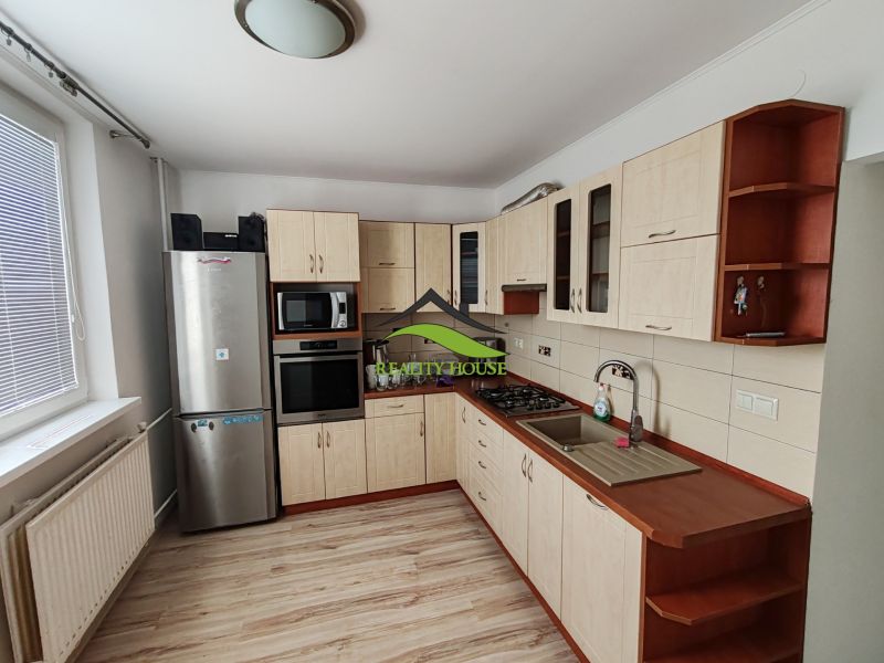 A kitchen in a 3-room apartment with a wooden decor floor and appliances.